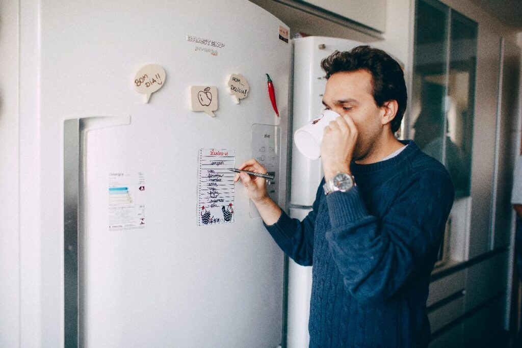 Resident planning daily goals and routine on refrigerator schedule in sober living home