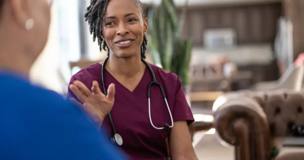 Black female healthcare provider in scrubs with a stethoscope having a conversation with a patient