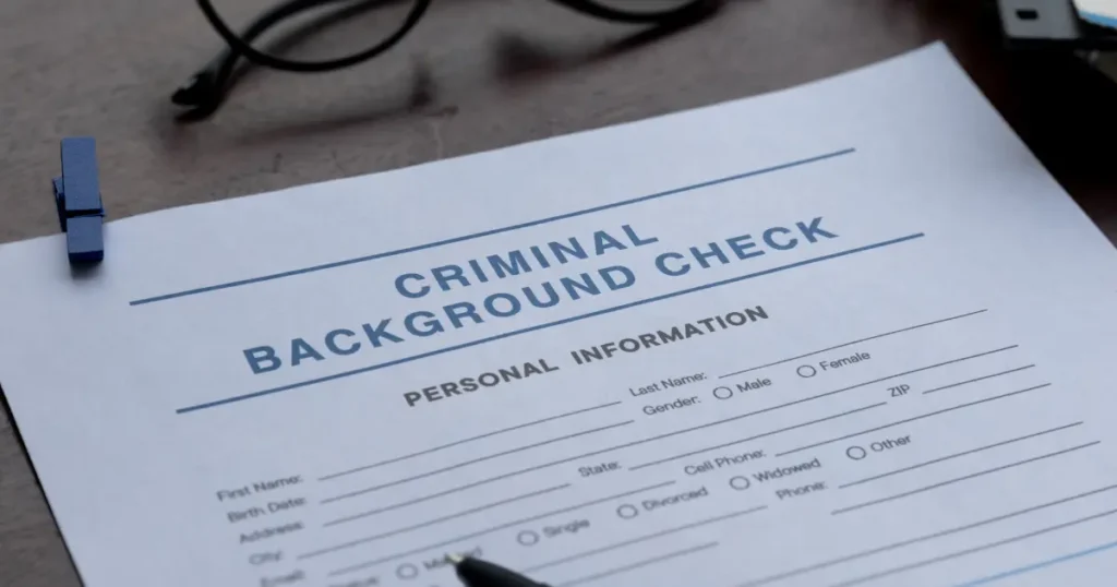 Criminal background check form with personal information fields on a desk with a pen and glasses