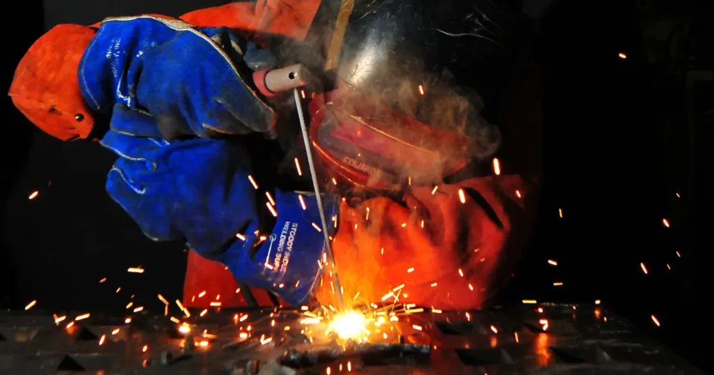 Welder in protective gear and helmet working with sparks flying — skilled trades work