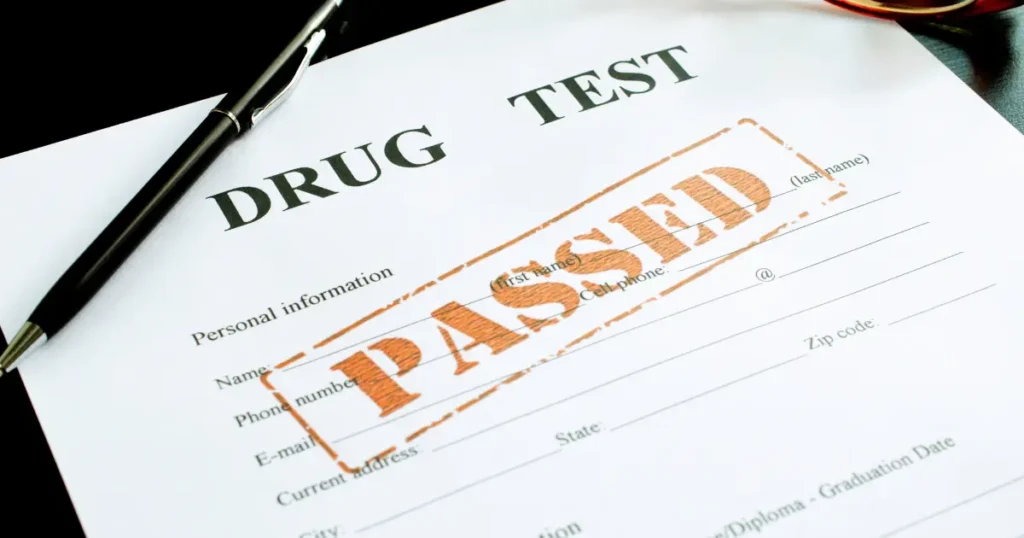 Drug test form with a passed stamp and pen on a dark surface