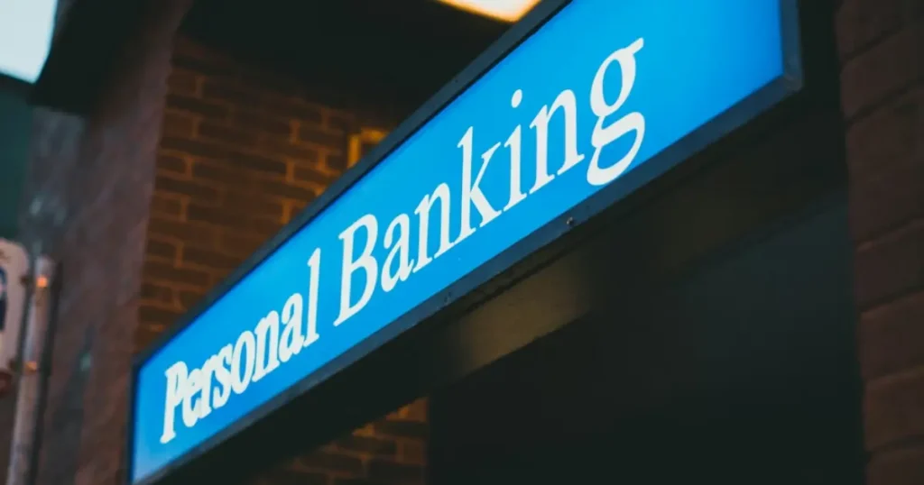 Blue illuminated Personal Banking sign on a brick building exterior