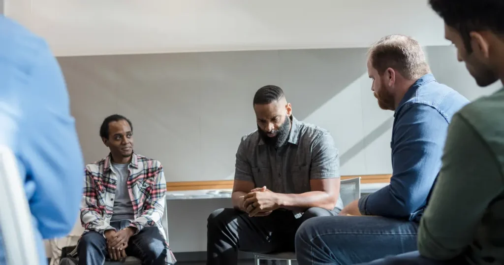 Diverse group of men sitting in a circle during a court-ordered group program session