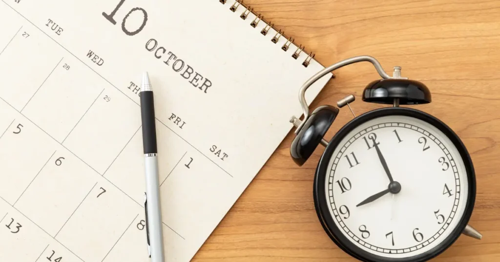 Calendar and alarm clock on a wooden surface illustrating time and deadlines