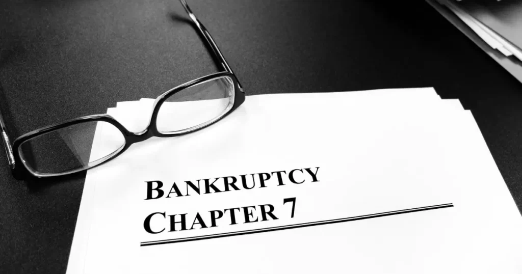 Bankruptcy Chapter 7 filing document with reading glasses on a dark surface