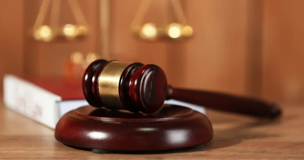 Judge's gavel on a wooden surface with scales of justice blurred in the background
